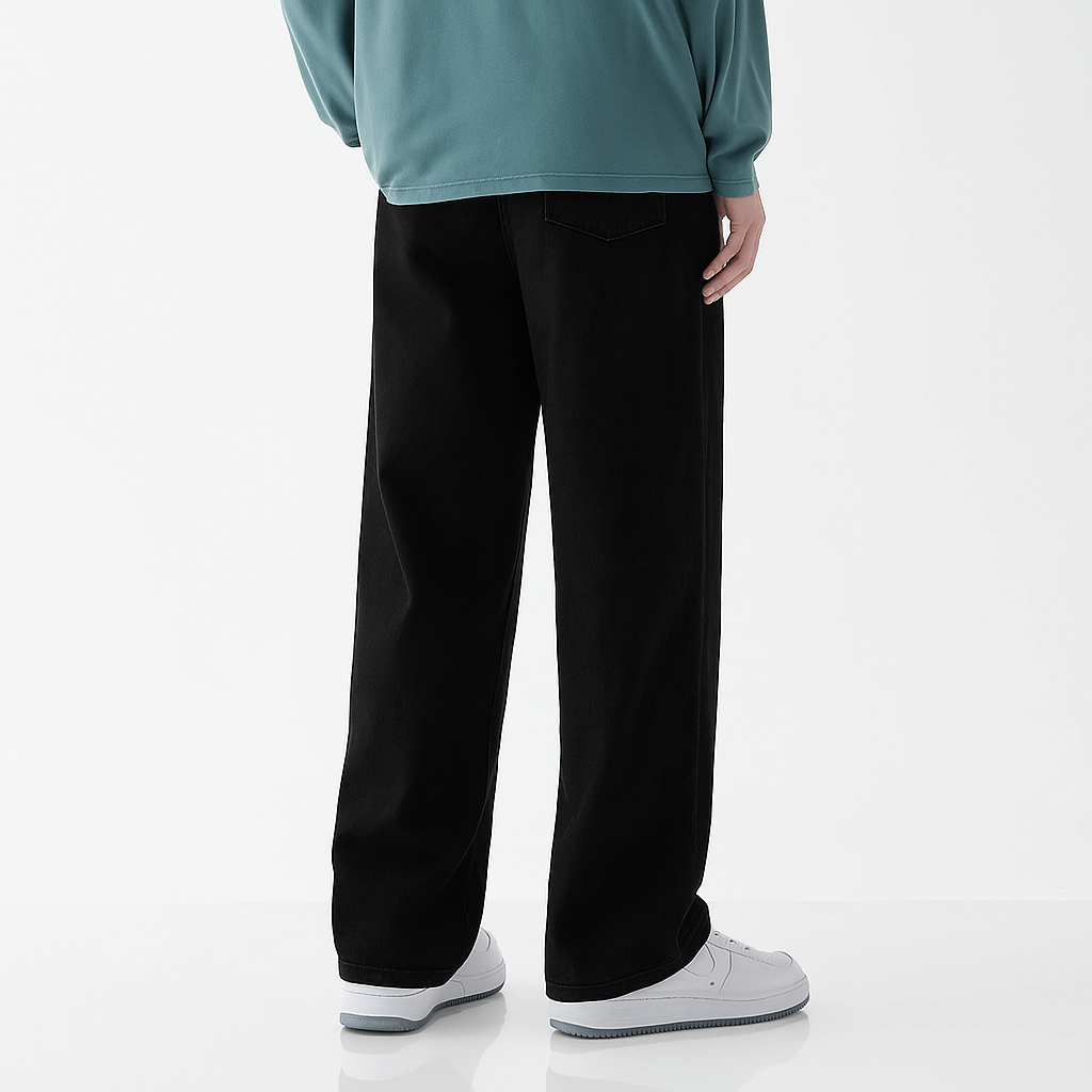 Man wearing black wide-leg relaxed fit denim jeans with teal long sleeve top and white sneakers, back view.