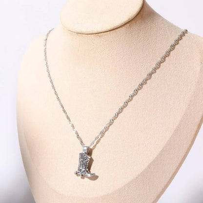 Silver necklace with intricate western cowboy boot charm pendant on twisted chain displayed on jewelry bust