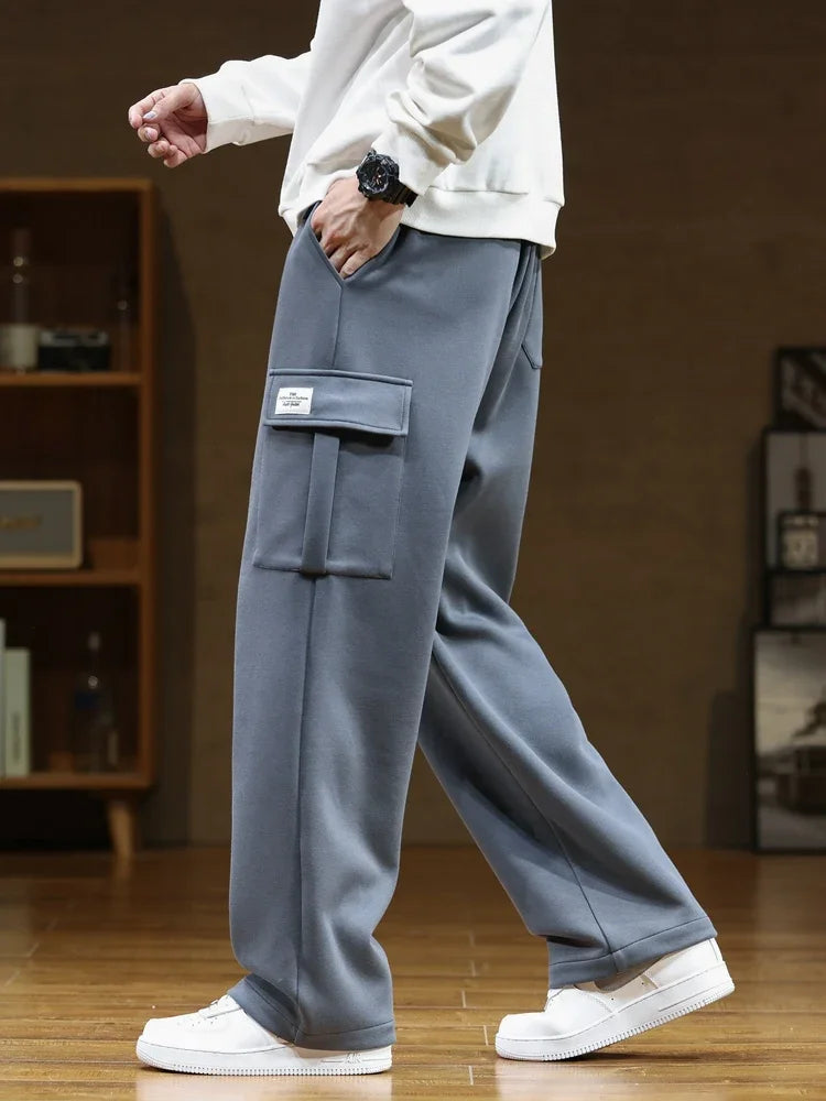Man wearing relaxed fit gray cargo pocket sweatpants with white sneakers and cream sweatshirt, side view.