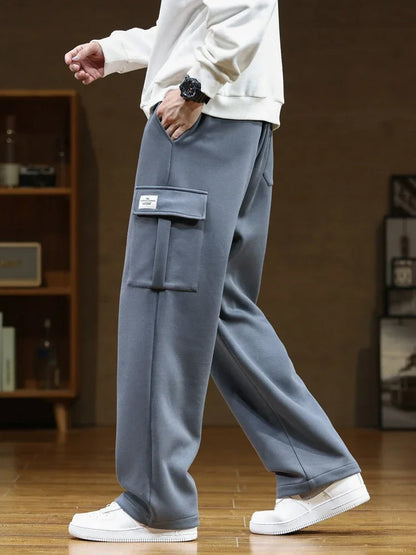 Man wearing relaxed fit gray cargo pocket sweatpants with white sneakers and cream sweatshirt, side view.