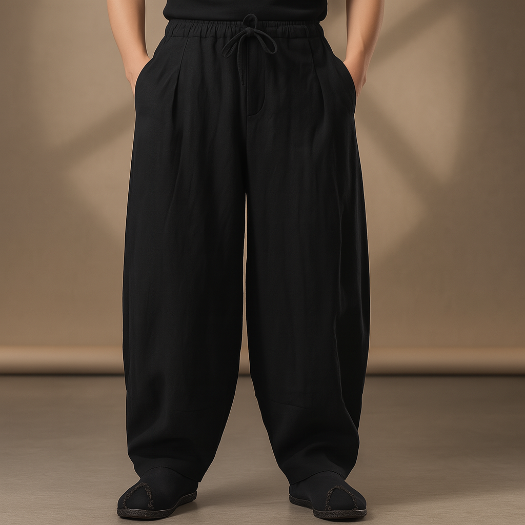 Black wide-leg linen drawstring pants for men with elastic waist, relaxed fit, side pockets, and black flat shoes.