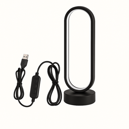 Black oval LED desk lamp with USB cable and inline controller, emitting warm white light, on circular base