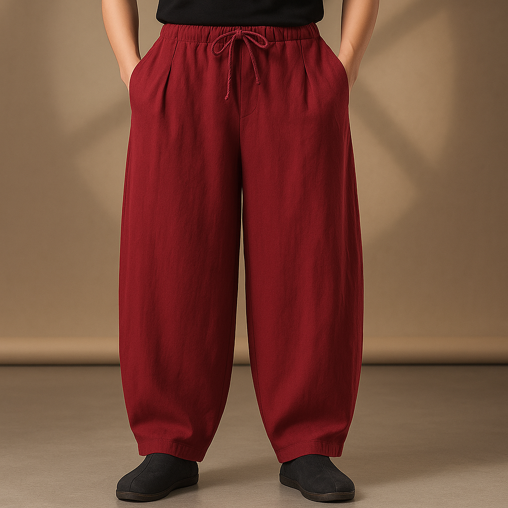 Men's burgundy wide-leg linen pants with drawstring waist and side pockets, paired with black slip-on shoes.