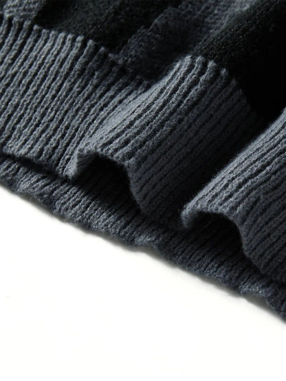 Close-up of dark grey wool knit oversized men's sweater showing ribbed hem detail and abstract texture pattern