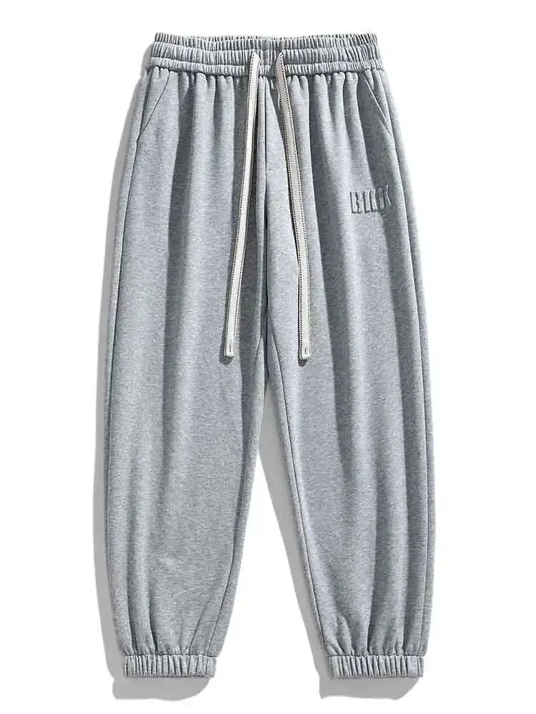 Gray men's drawstring sweatpants with elastic waistband, side pockets, ribbed cuffs, and small logo detail.