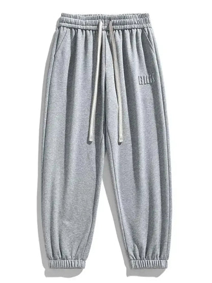 Gray men's drawstring sweatpants with elastic waistband, side pockets, ribbed cuffs, and small logo detail.