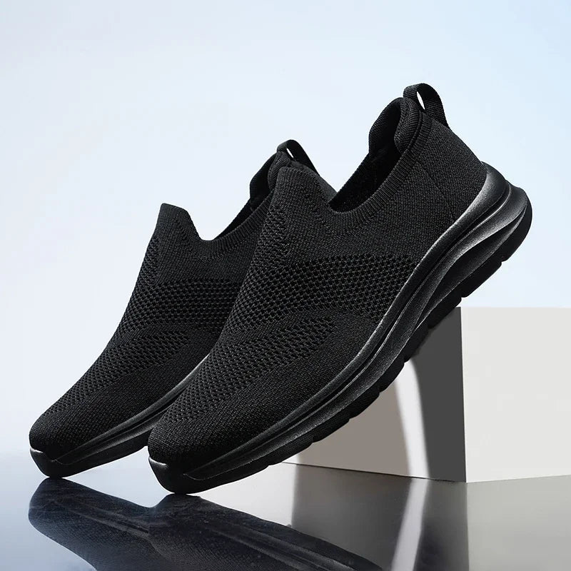 Black slip-on mesh sneakers for women with cushioned sole and breathable knit upper on display stand