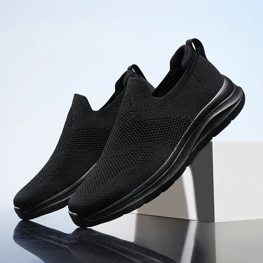 Black slip-on mesh sneakers for women with cushioned sole and breathable knit upper on display stand