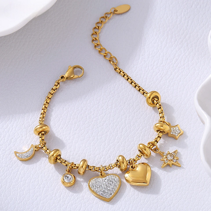 Gold heart charm bracelet with crystal moon star accents for women on white textured background