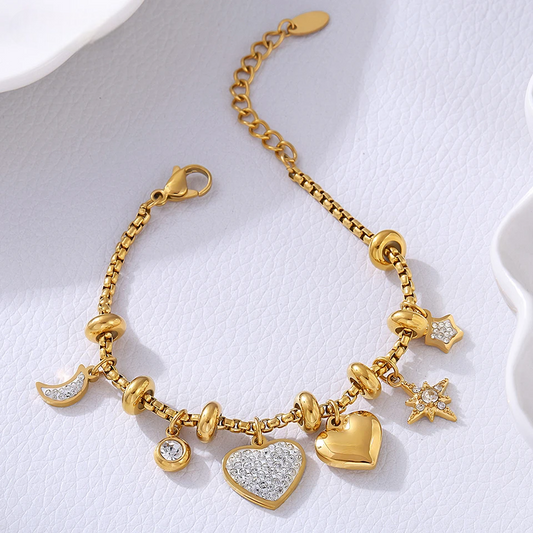 Gold heart charm bracelet with crystal moon star accents for women on white textured background