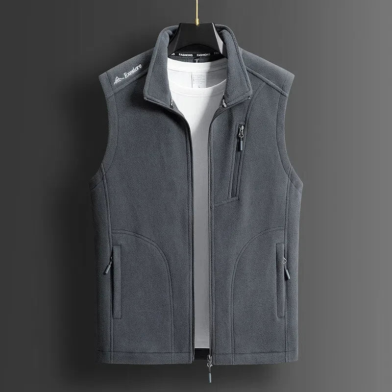 Gray men's fleece zip-up vest with stand collar, chest pocket, and side pockets, displayed on hanger over white tee