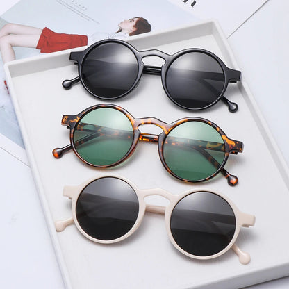 Three round frame sunglasses in black, tortoise with green lenses, and cream displayed on white tray with UV400 protection