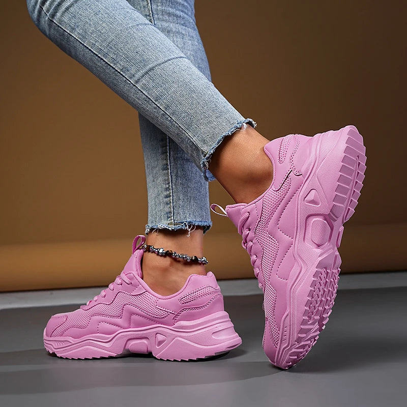Women's pink chunky mesh lace-up sneakers with thick platform sole, styled with distressed jeans and beaded anklet.