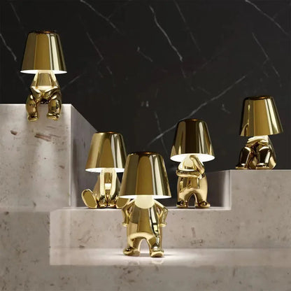 Gold metallic dog figurine desk lamps in various poses arranged on marble steps, glowing with warm ambient light.