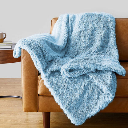 Soft light blue faux fur shaggy throw blanket draped over tan leather armchair in modern living room setting