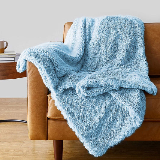 Soft light blue faux fur shaggy throw blanket draped over tan leather armchair in modern living room setting