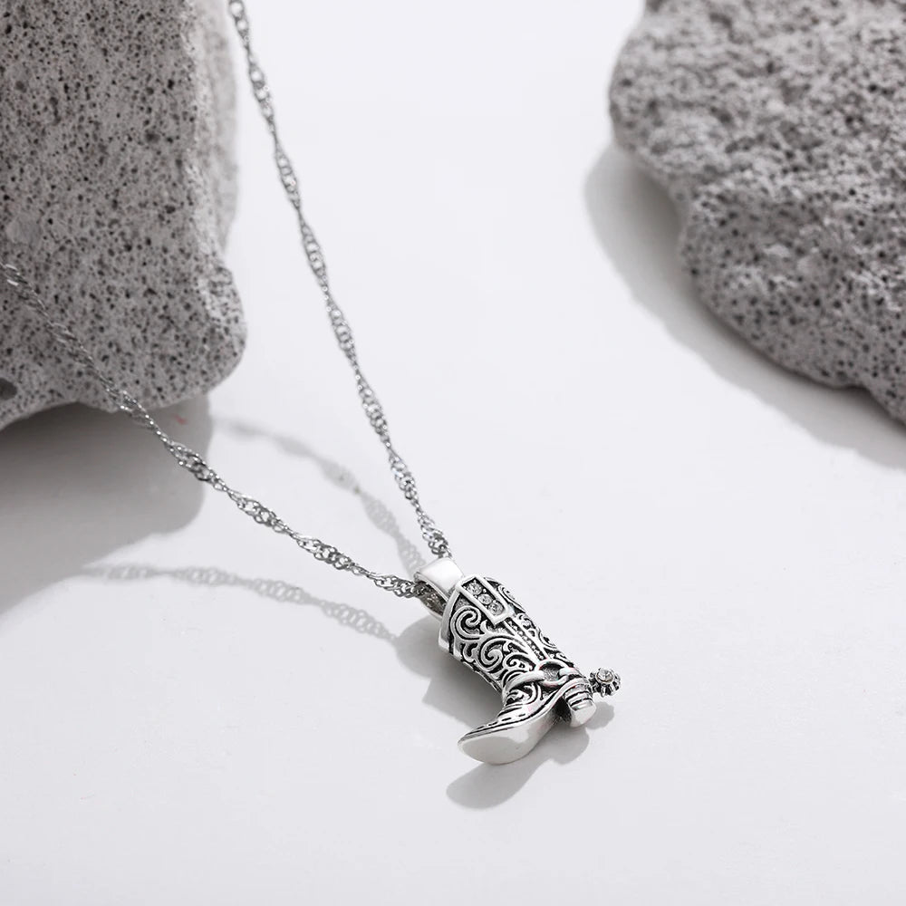Silver necklace with ornate western cowboy boot charm pendant featuring intricate scrollwork and crystal details on twisted chain