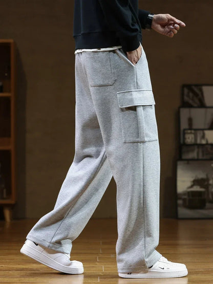 Man wearing light gray relaxed fit cargo pocket sweatpants with white Nike sneakers and black sweatshirt, side view.
