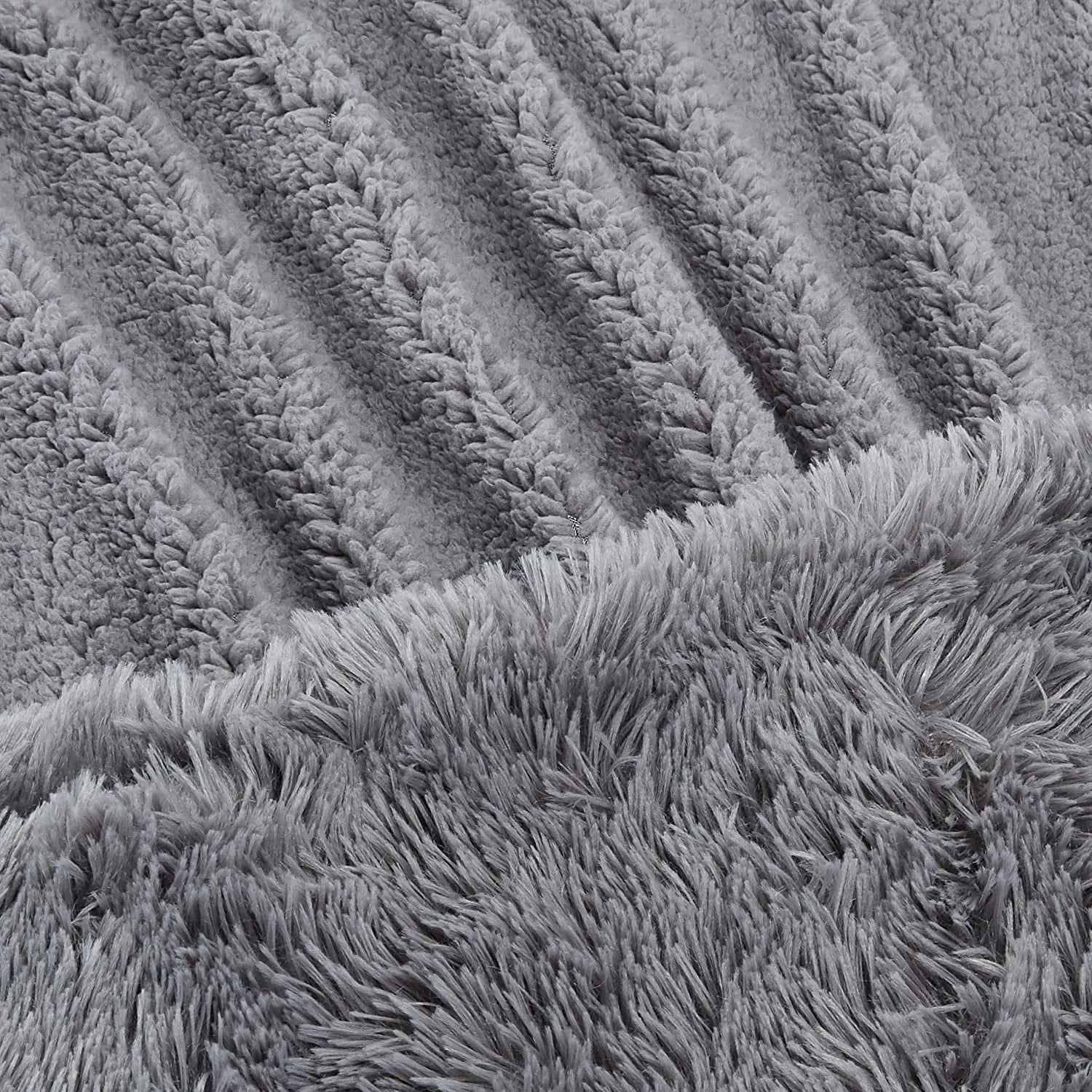 Gray faux fur plush throw blanket with diagonal ribbed texture pattern and long shaggy fringe edge detail.