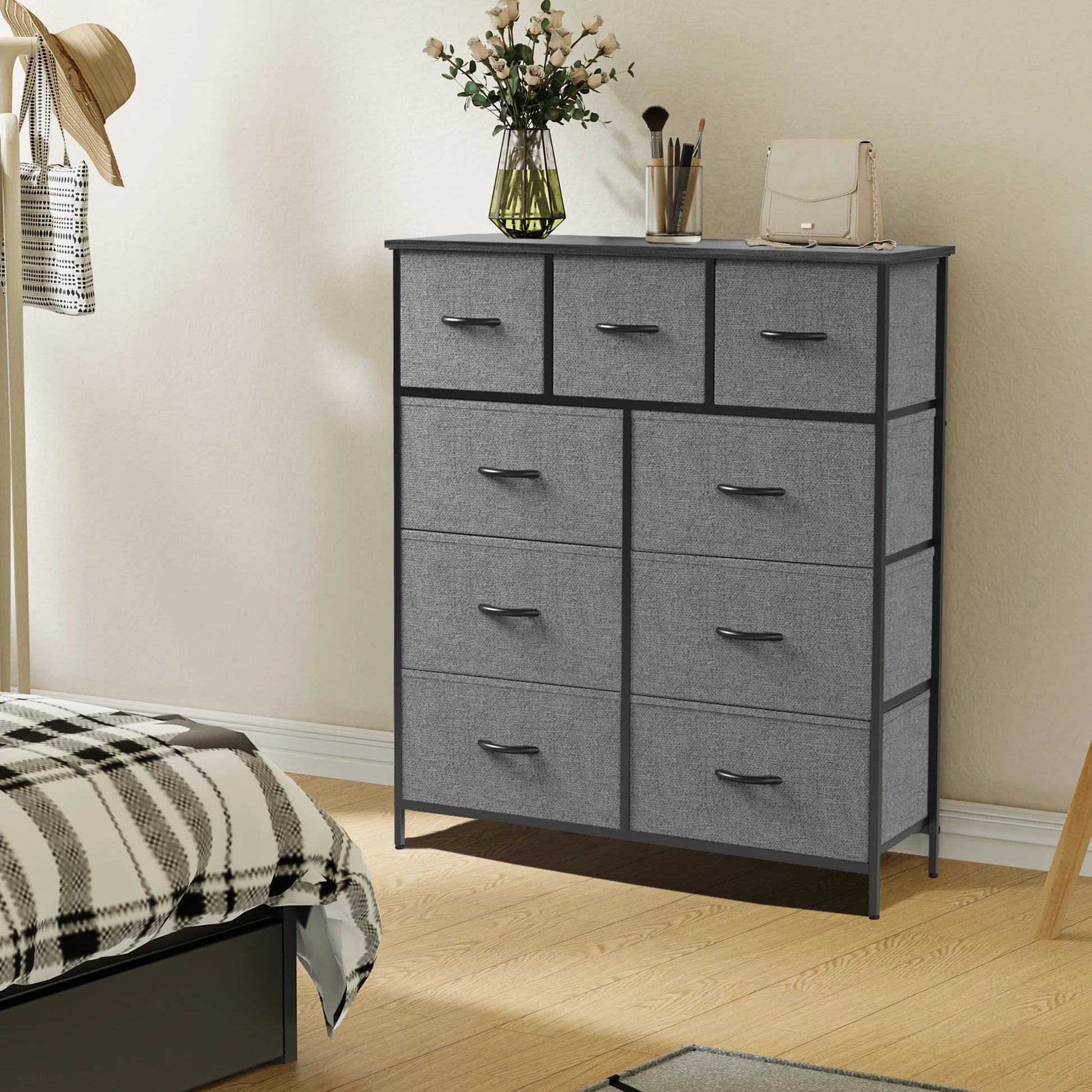 Gray fabric 9-drawer dresser with black steel frame and wood top, styled with flowers and accessories in a bedroom setting.