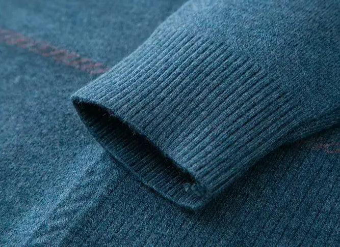 Close-up of teal wool blend sweater cuff showing ribbed knit detail and subtle red pattern on sleeve body.