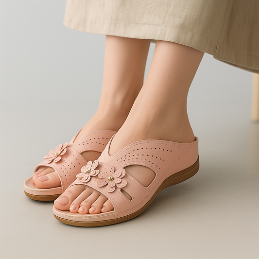 Women's pink slip-on sandals with flower decorations and perforated cutout design on neutral background
