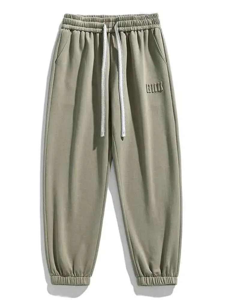 Men's sage green drawstring sweatpants with elastic waistband, side pockets, ribbed cuffs, and embroidered logo detail.