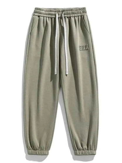 Men's sage green drawstring sweatpants with elastic waistband, side pockets, ribbed cuffs, and embroidered logo detail.
