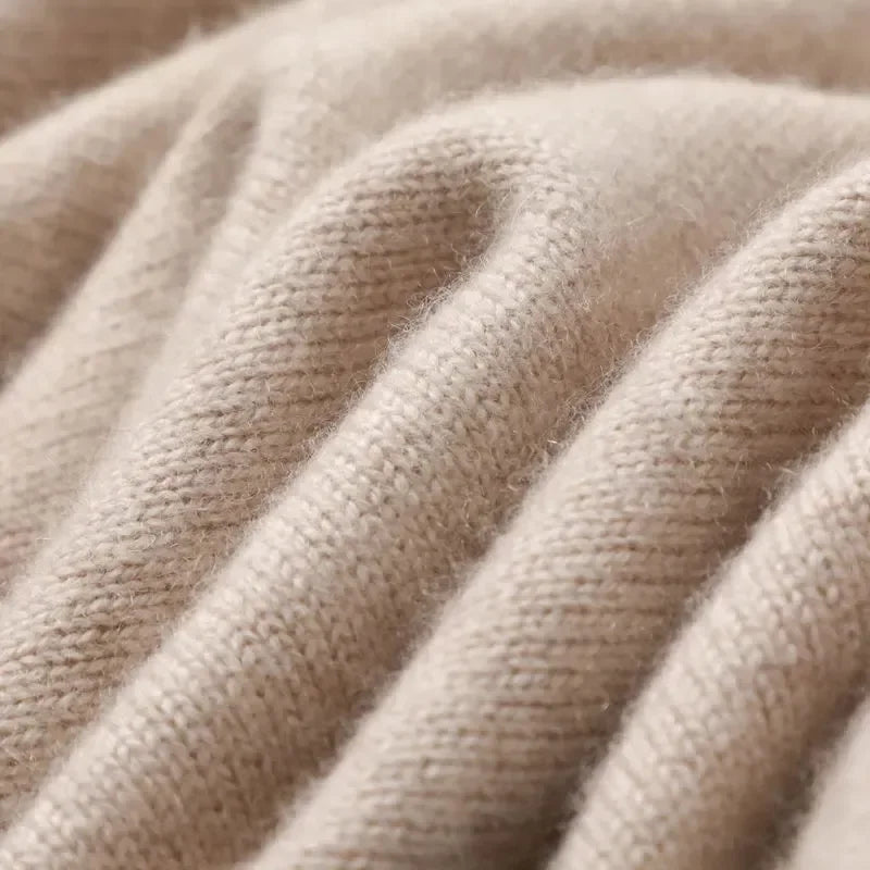 Close-up of soft beige cashmere blend knit fabric showing fine texture and gentle folds of men's crewneck sweater