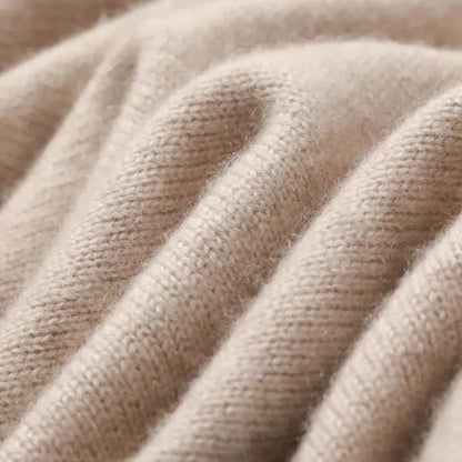 Close-up of soft beige cashmere blend knit fabric showing fine texture and gentle folds of men's crewneck sweater