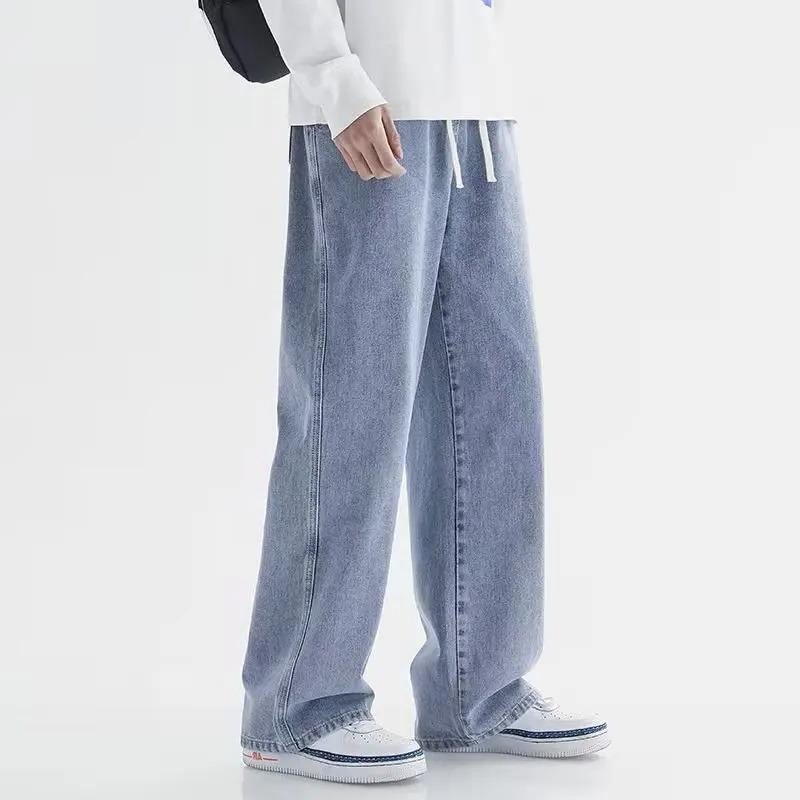 Men's wide-leg relaxed fit light blue denim jeans with drawstring waist, paired with white sneakers and sweatshirt