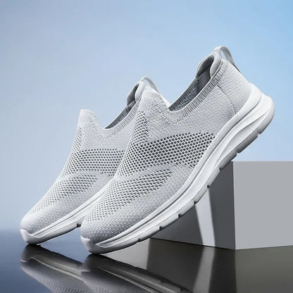 Light gray women's slip-on mesh sneakers with breathable knit upper and white sole, displayed on a gray block.