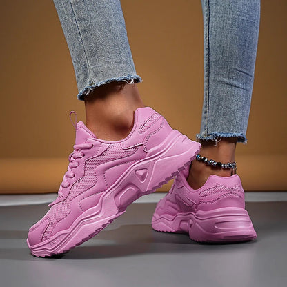Women's pink chunky mesh lace-up sneakers with thick sole, worn with frayed hem jeans and beaded anklet.