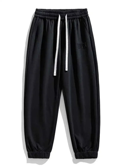 Black men's drawstring sweatpants with elastic waistband, white cord, ribbed cuffs, and embroidered logo detail.