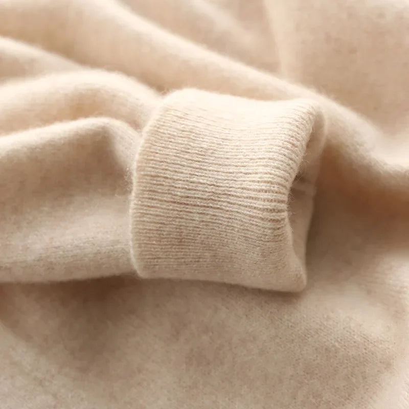 Close-up of a soft beige cashmere blend crewneck sweater showing ribbed cuff detail and luxurious fabric texture.