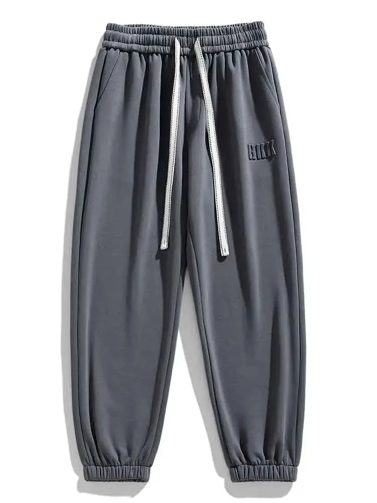 Gray men's drawstring sweatpants with elastic waistband, ribbed cuffs, side pockets, and embroidered logo detail.