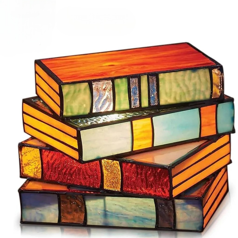 Tiffany-style stained glass lamp shaped like four stacked books in vibrant red, orange, teal, and multicolor panels