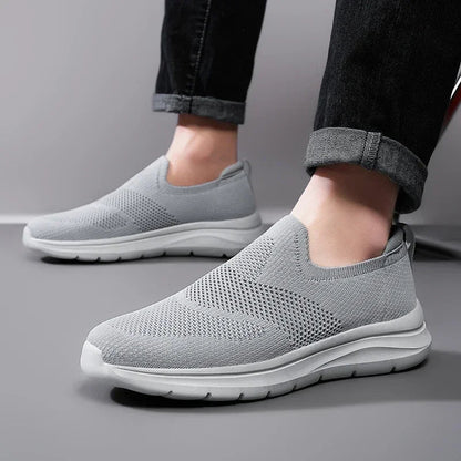 Gray slip-on mesh sneakers with white sole, shown on feet with rolled dark jeans, lightweight breathable design