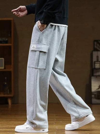 Man wearing light gray relaxed fit cargo pocket sweatpants with elastic waist, paired with white Nike Air Force 1 sneakers.