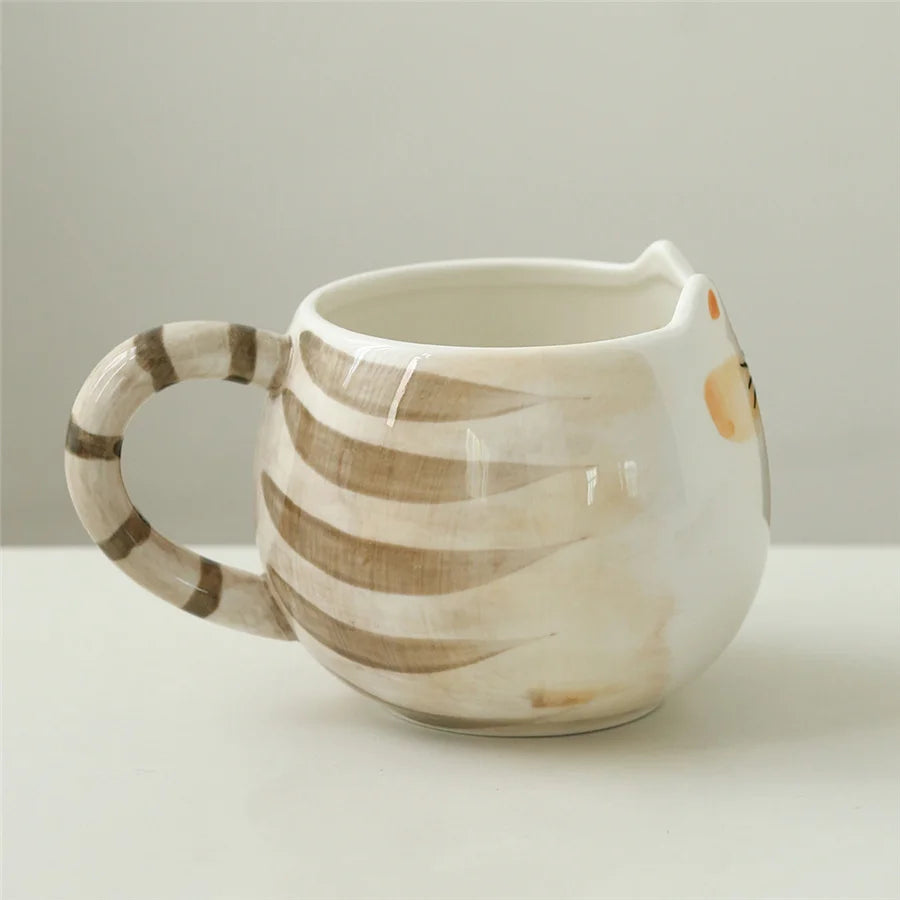 Ceramic white cat-shaped coffee mug with brown tabby stripes, cat ear rim, and striped tail handle