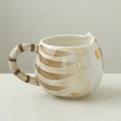 Ceramic white cat-shaped coffee mug with brown tabby stripes, cat ear rim, and striped tail handle