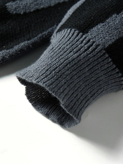 Close-up of dark gray wool knit sweater cuff showing ribbed hem and abstract black pattern texture detail.