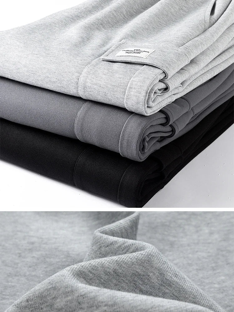 Three folded men's relaxed fit sweatpants stacked in light gray, dark gray, and black with close-up fabric detail.