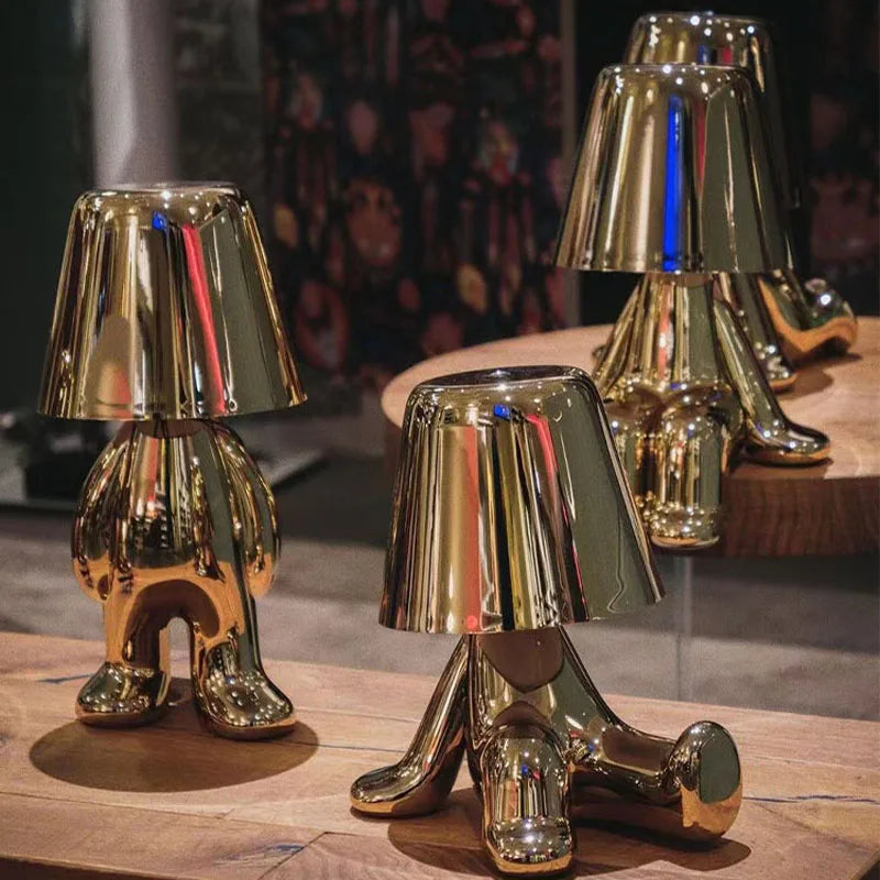 Gold metallic dog figurine desk lamps with lampshade heads in various poses displayed on wooden surface